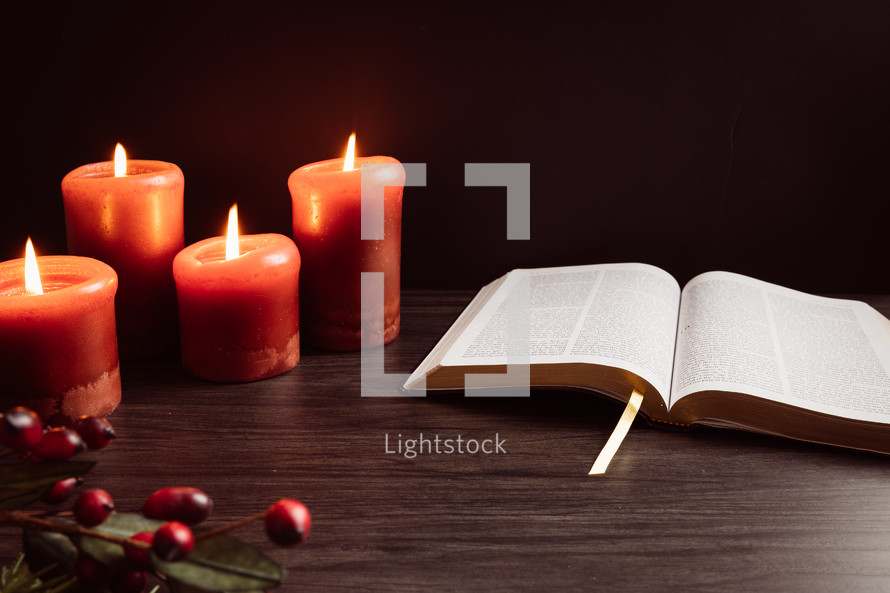 Christmas berries and candles with open Bible