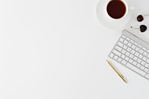 coffee cup, saucer, pen, cherries, and computer keyboard on white 
