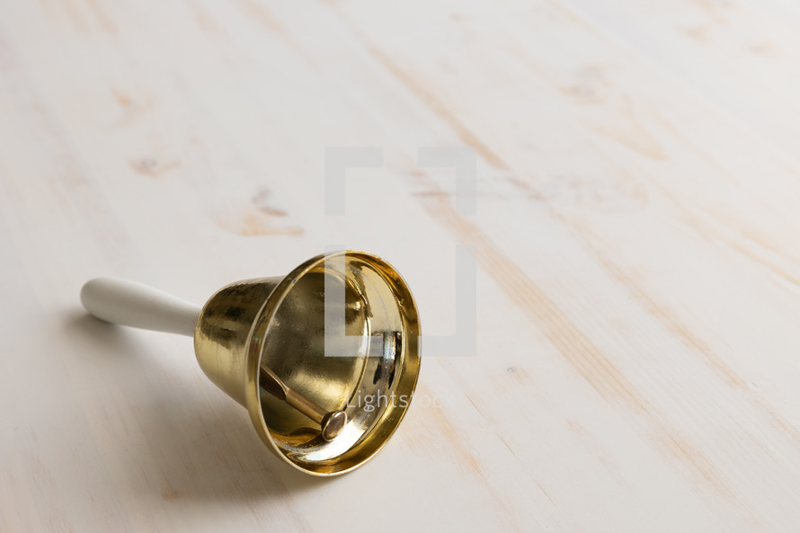 gold and white bell on white wood