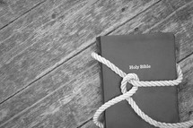 knot in rope around a Bible on a wood background 