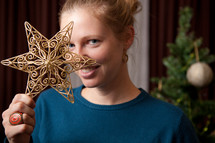woman holding a star ornament in front of her face