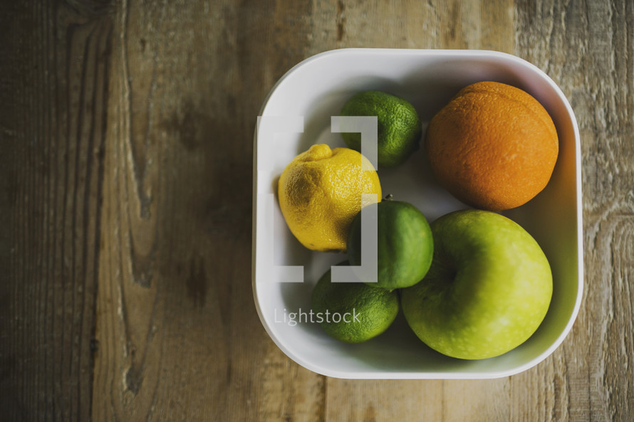 A bowl of fruit on a wooden table.
