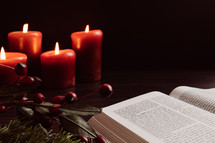 Christmas garland with berries and candles and open Bible
