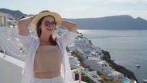 Tourist travel woman in Oia, Santorini, Greece. Happy young woman enjoying view. Beautiful girl visiting the Greek island.