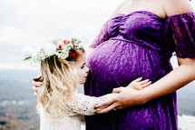 daughter and pregnant woman holding her belly 