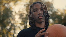 Portrait of a smiling young man playing basketball on a sunny day