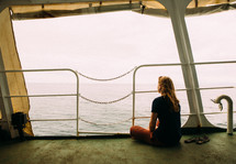 A woman sitting on a ferry looking out at the water 