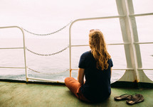 a woman looking off the back of a ferry 