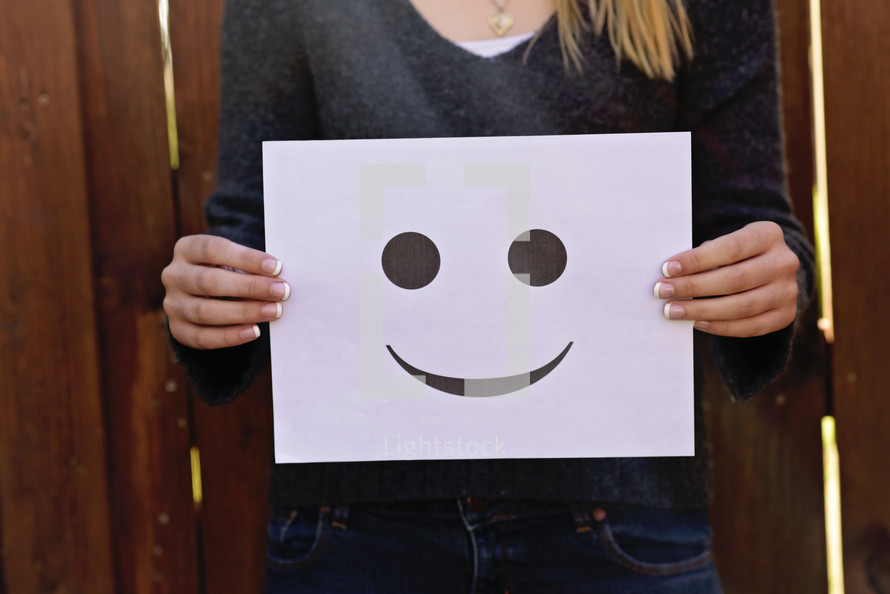 a woman holding a happy face sign 