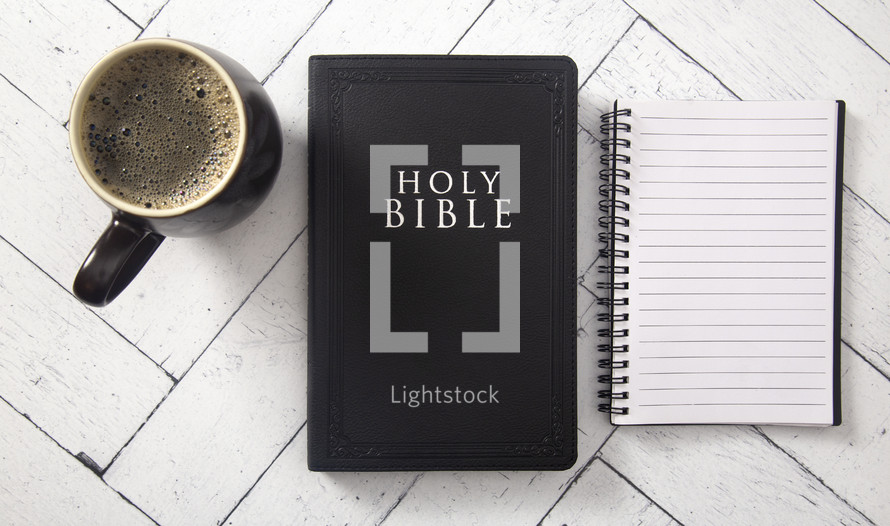 notebook, coffee cup, and Bible on a white wood background 