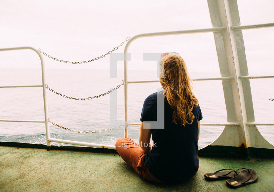 a woman looking off the back of a ferry 