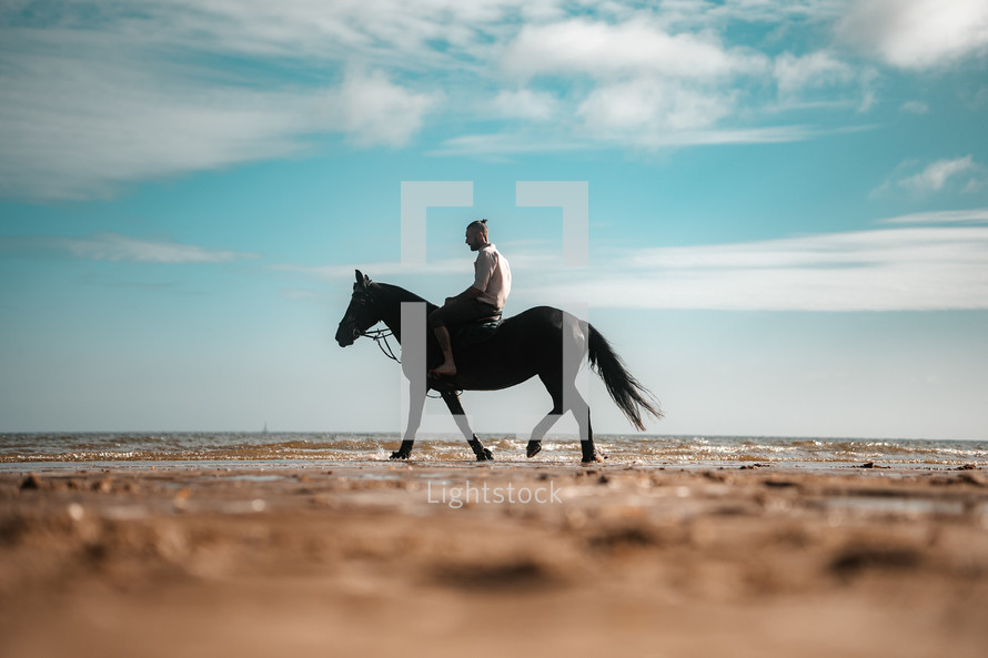 Horse riding on a beach, equestrian man riding on a horse