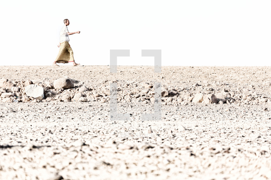 man walking across a desert 
