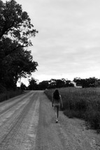a woman walking down a dirt road 