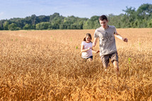children running in a field of wheat 