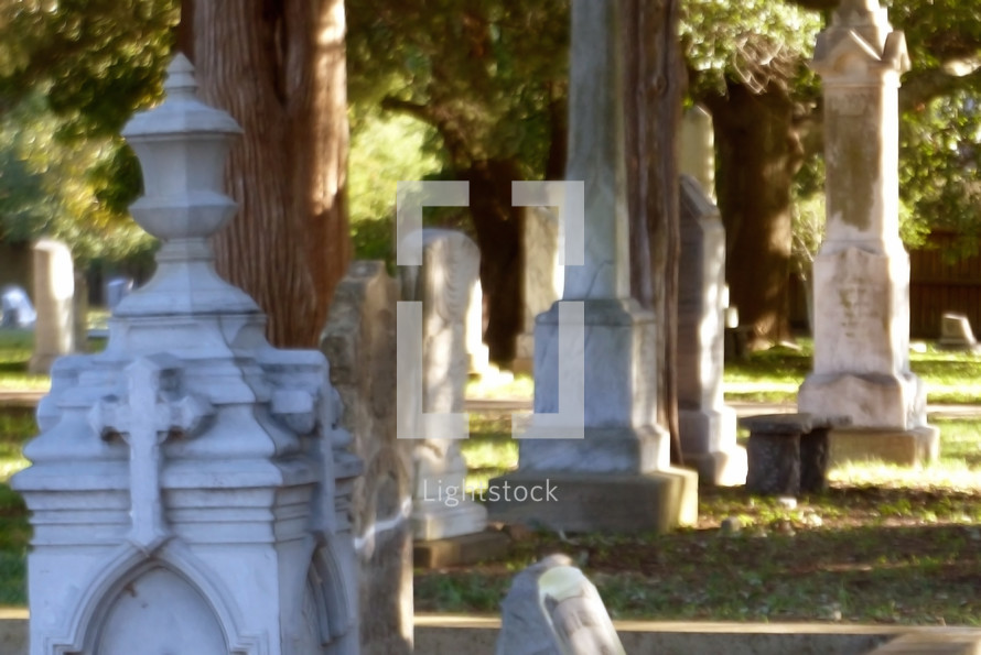 soft focus cemetery with old carved monuments and sunny side lighting