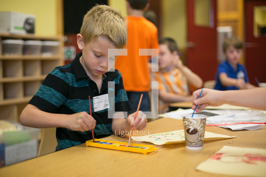 A little boy using watercolors in classroom