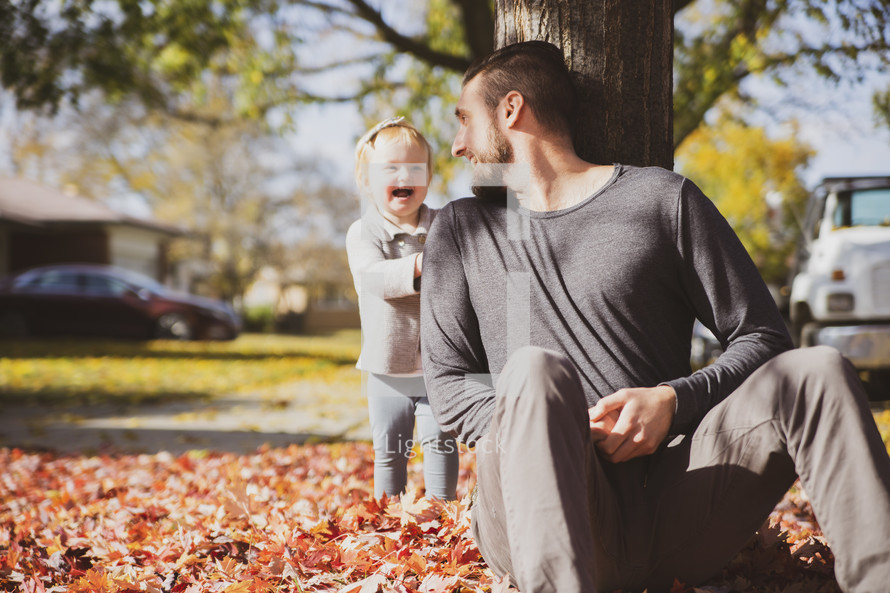 a father and little girl playing in fall leaves 