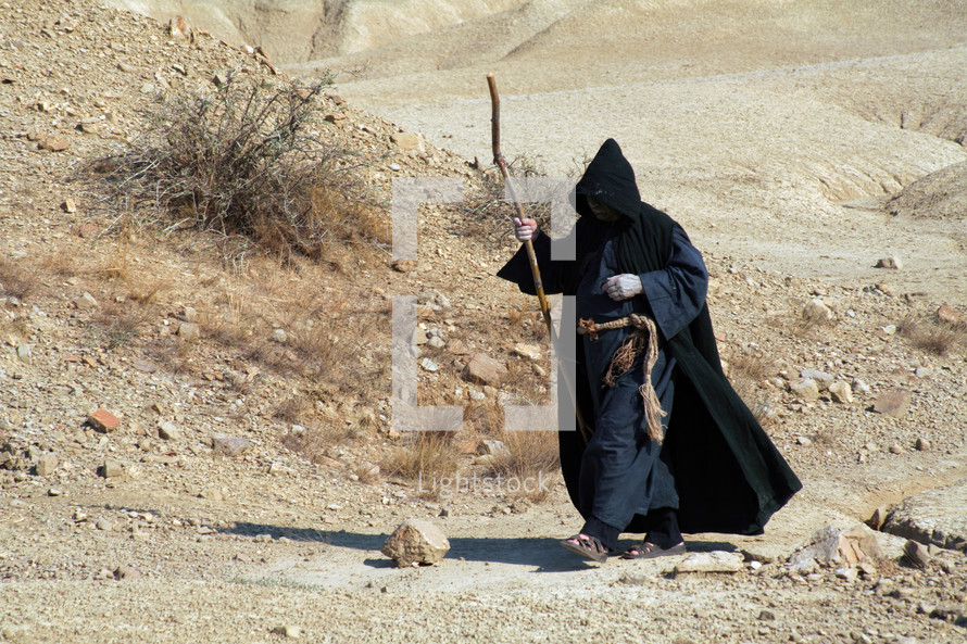 Hermit walking through the desert. Religious concept of enlightenment through fasting and prayer.
