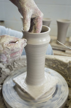 potter shaping a tall vase 