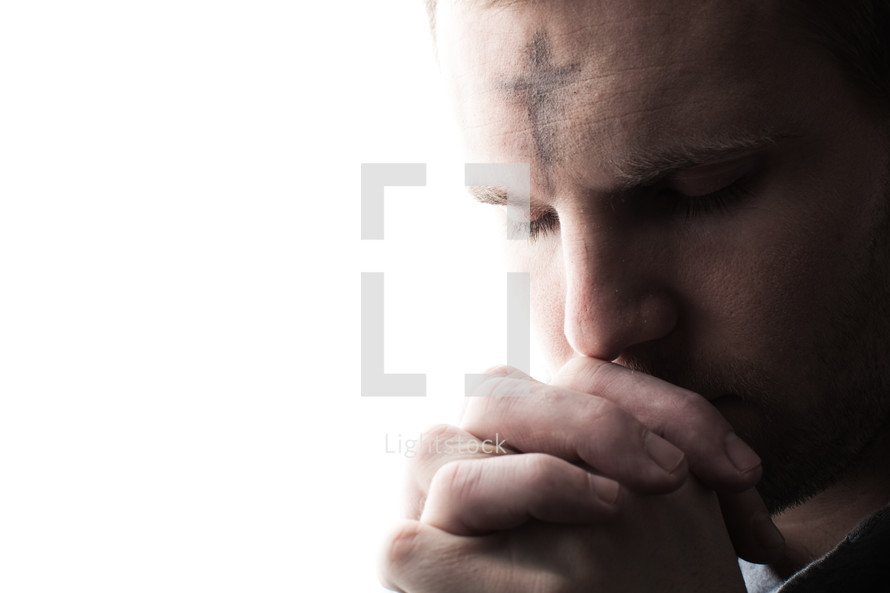 A man with ashes on his forehead in prayer for Ash Wednesday