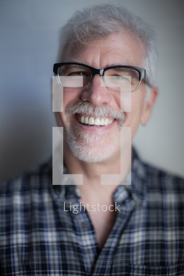 face of a man wearing reading glasses with a white beard 