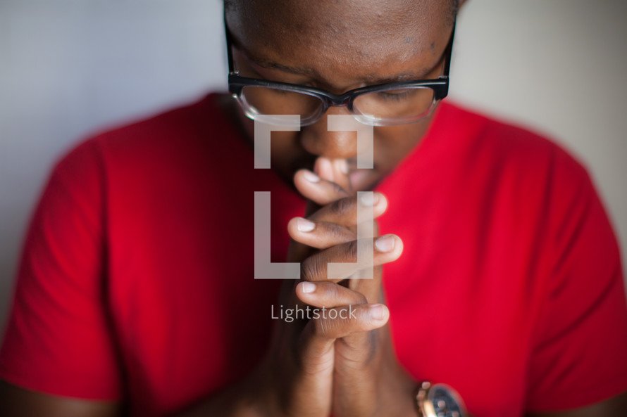 African-American man with praying hands and head bowed 