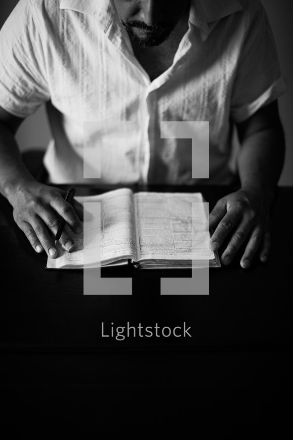 A man sitting at a table, studying a Bible.