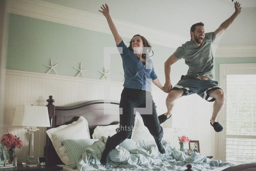 couple jumping on a bed 
