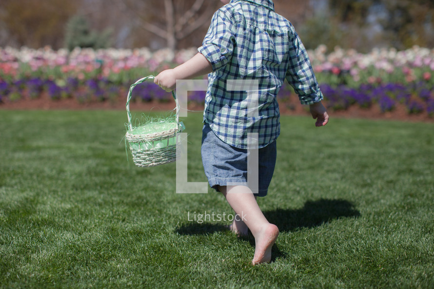 Young boy holding an Easter basket, walking in a garden of  flowers