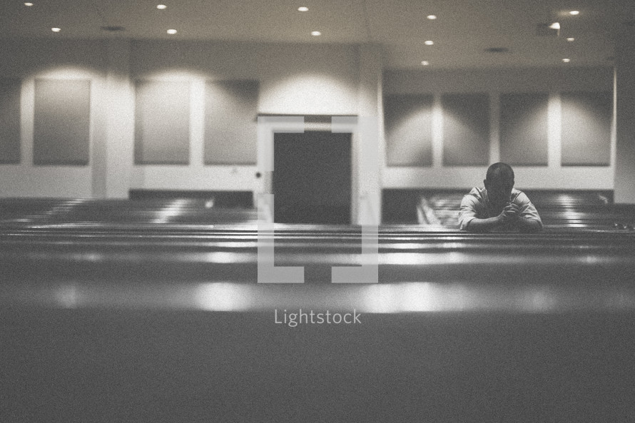 man alone in prayer in an empty church