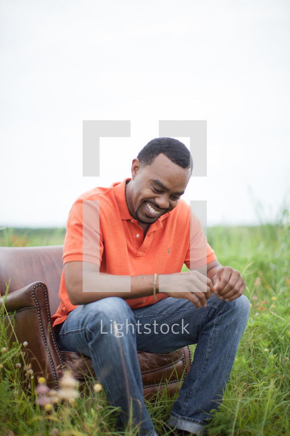 man sitting in a chair in field in thought 