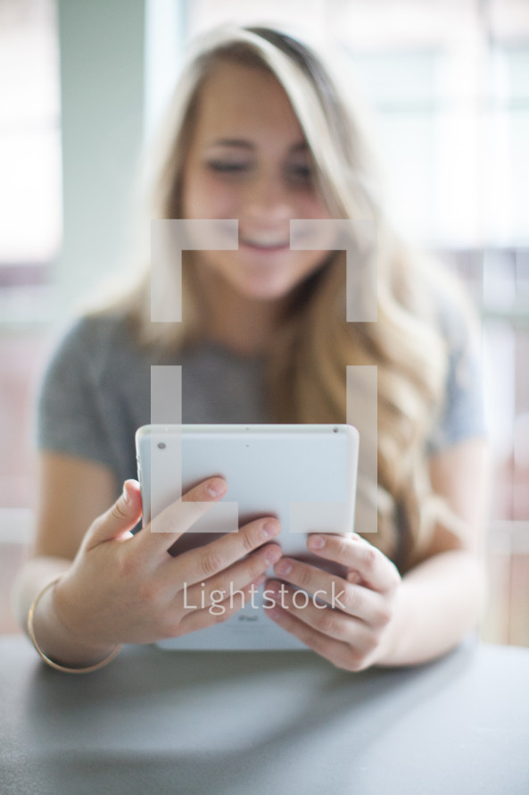 blonde woman looking at an iPad screen 