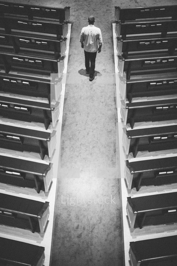 man walking down the aisle of an empty church 