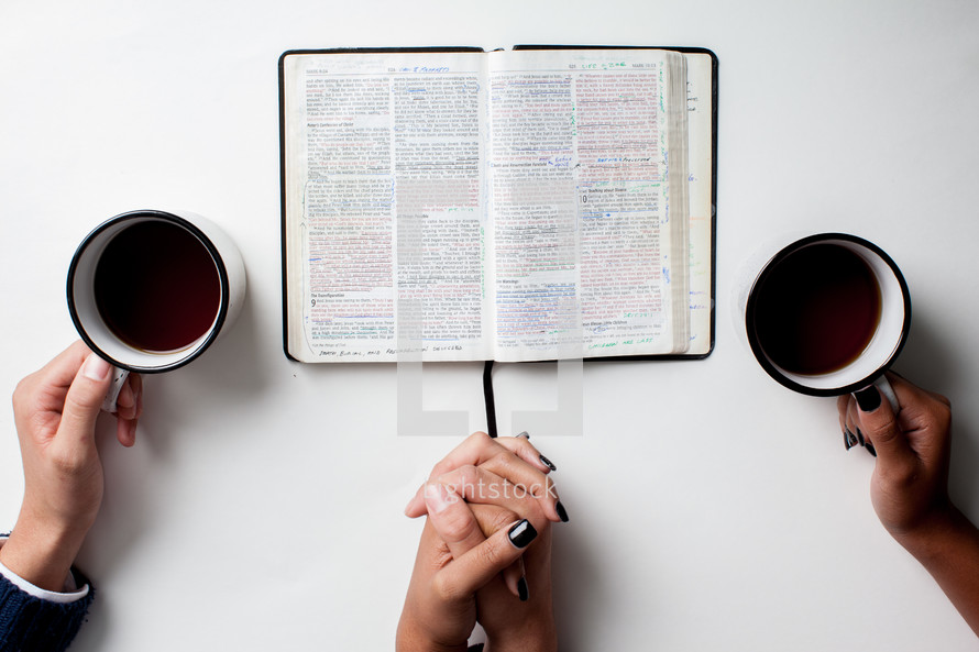 couple praying together with an open Bible and coffee mug