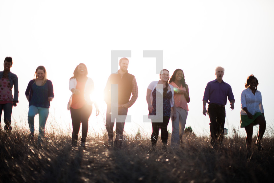 group of people walking outdoors in a field at sunset 