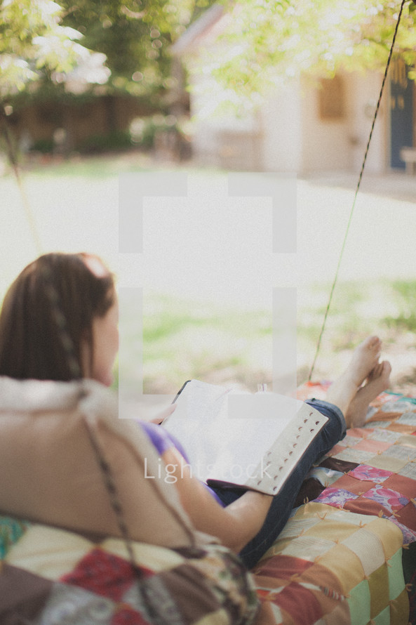 woman reading a Bible outdoors in her backyard 