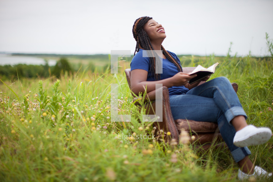 woman reading a Bible sitting in chair outdoors 