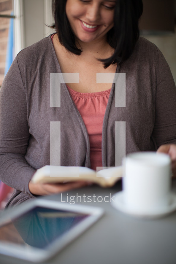 Latino woman reading a Bible and a coffee cup 