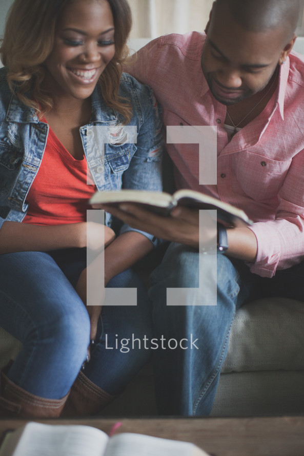 couple reading a Bible together on a couch 