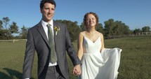 Happy bride and groom walking together outside in summer wedding.