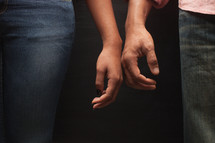 couple standing next to each other touching hands
