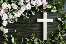 cross and pink flowers on black wood background 