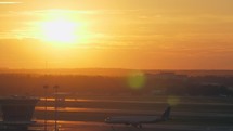 Airport view with moving plane at golden sunset