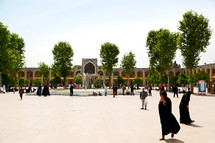 people in a courtyard near a mosque