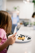 Little girl eating pancakes for breakfast 