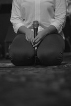 woman on her knees holding a microphone 