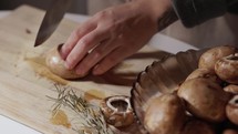 Woman Cutting Mushroom On Wooden Chopping Board. - close up shot