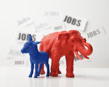 blue donkey and a red elephant are againts a white wall that has job text in the background for a 2020 political issue of employment rate and the economy.