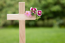 wooden cross with pink flowers outdoors 